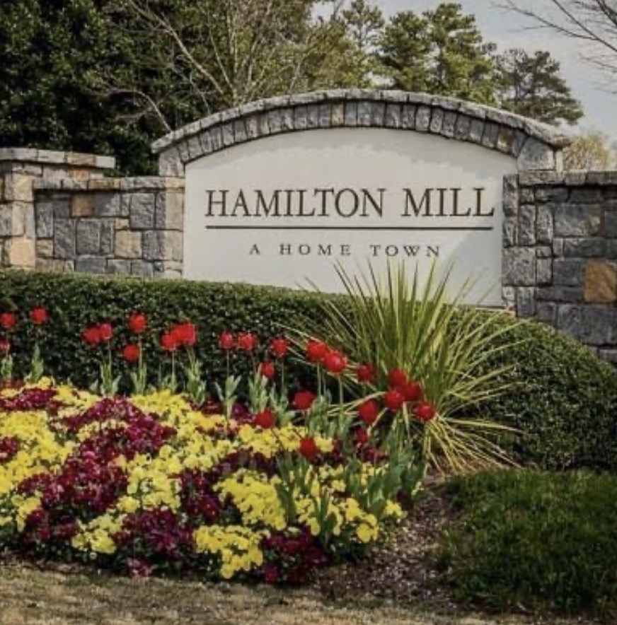 Hamilton Mill entrance sign with stone walls and flower beds