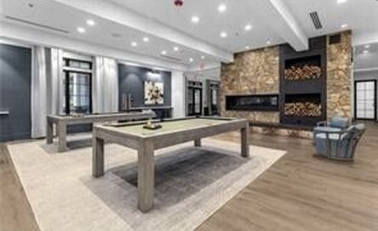 Clubhouse game room with pool table and stone fireplace