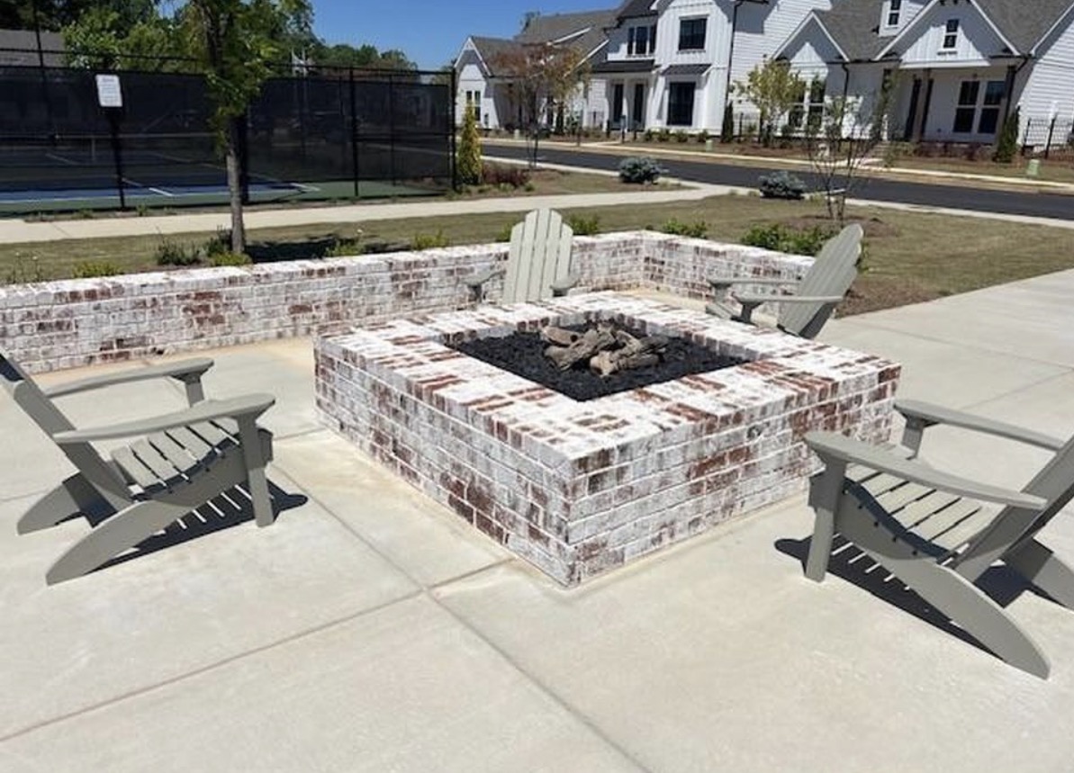 Brick fire pit surrounded by Adirondack chairs at Sawnee Village